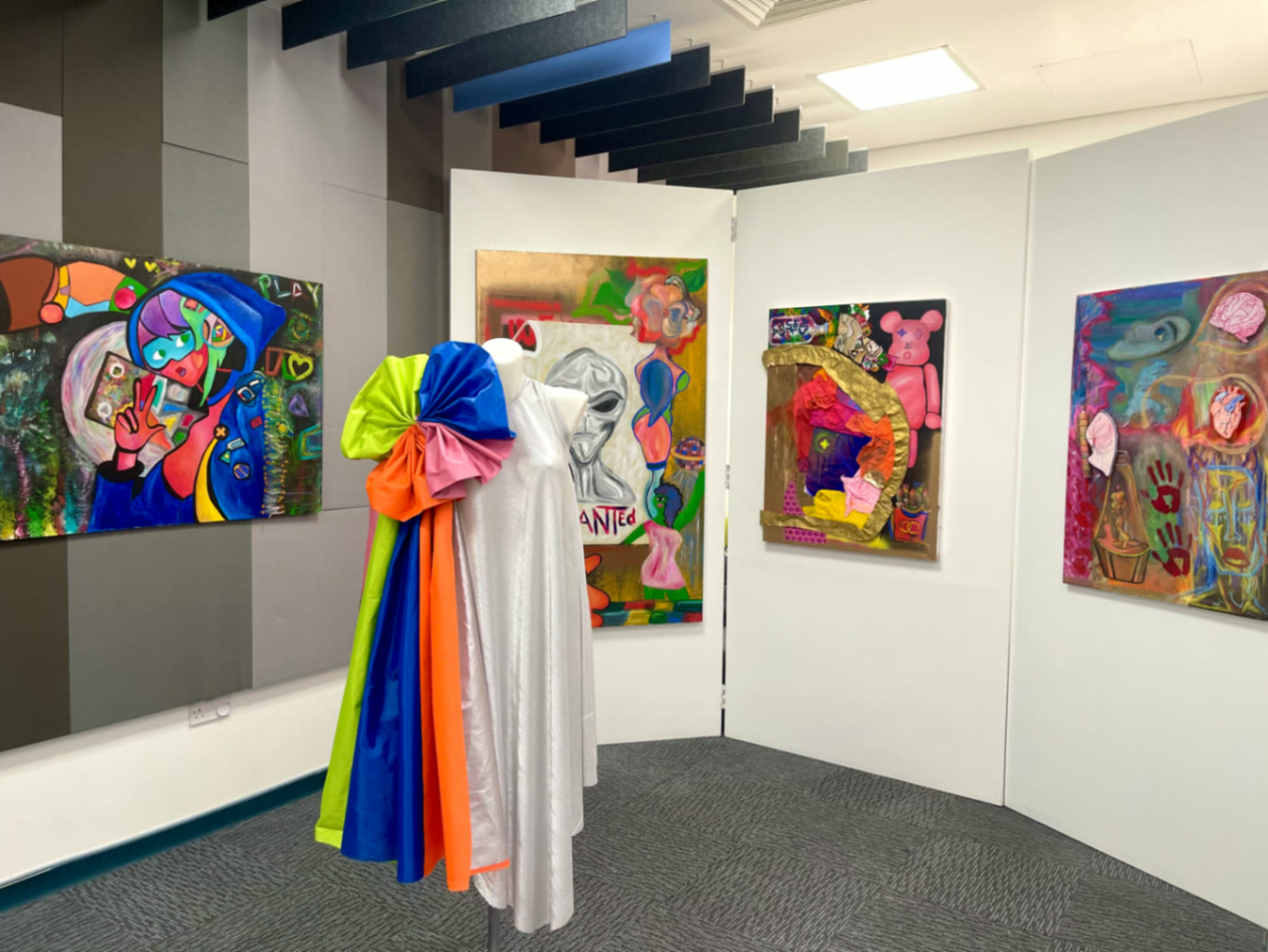The rainbow cape beside the Wanted canvases